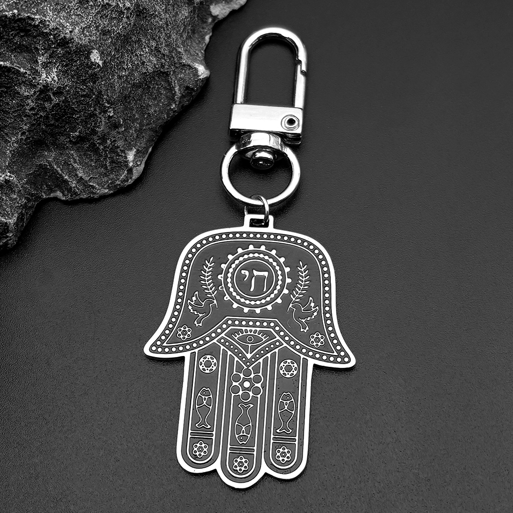 Porte-clés Hamsa en acier inoxydable avec cordon noir tressé et détails hébraïques.
