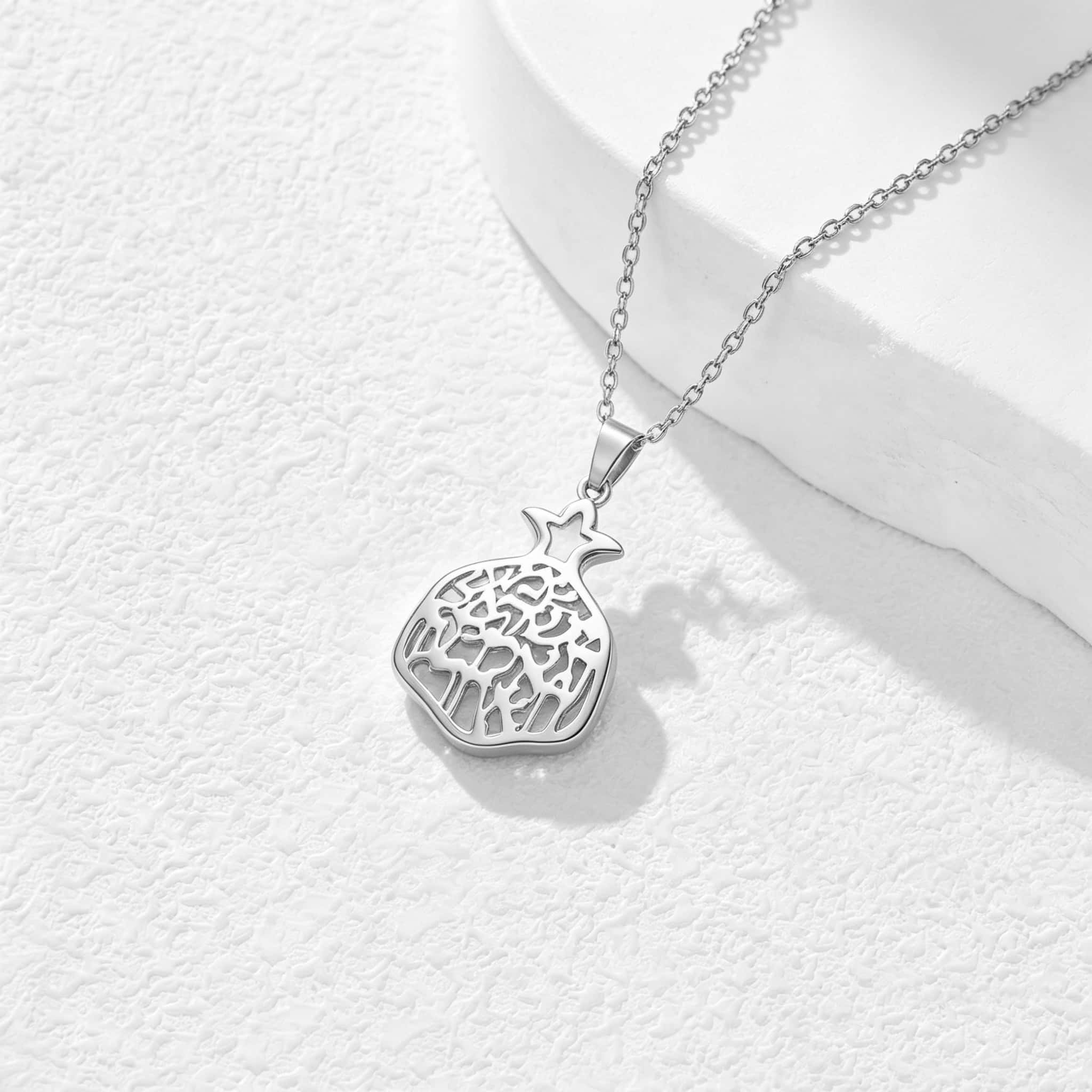 Pendentif grenade argenté photographié en lumière naturelle