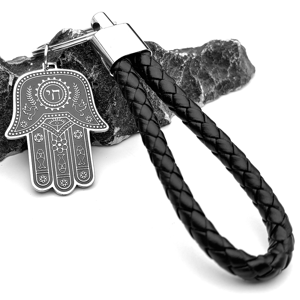 Porte-clés Hamsa en acier inoxydable avec cordon noir tressé et détails hébraïques.